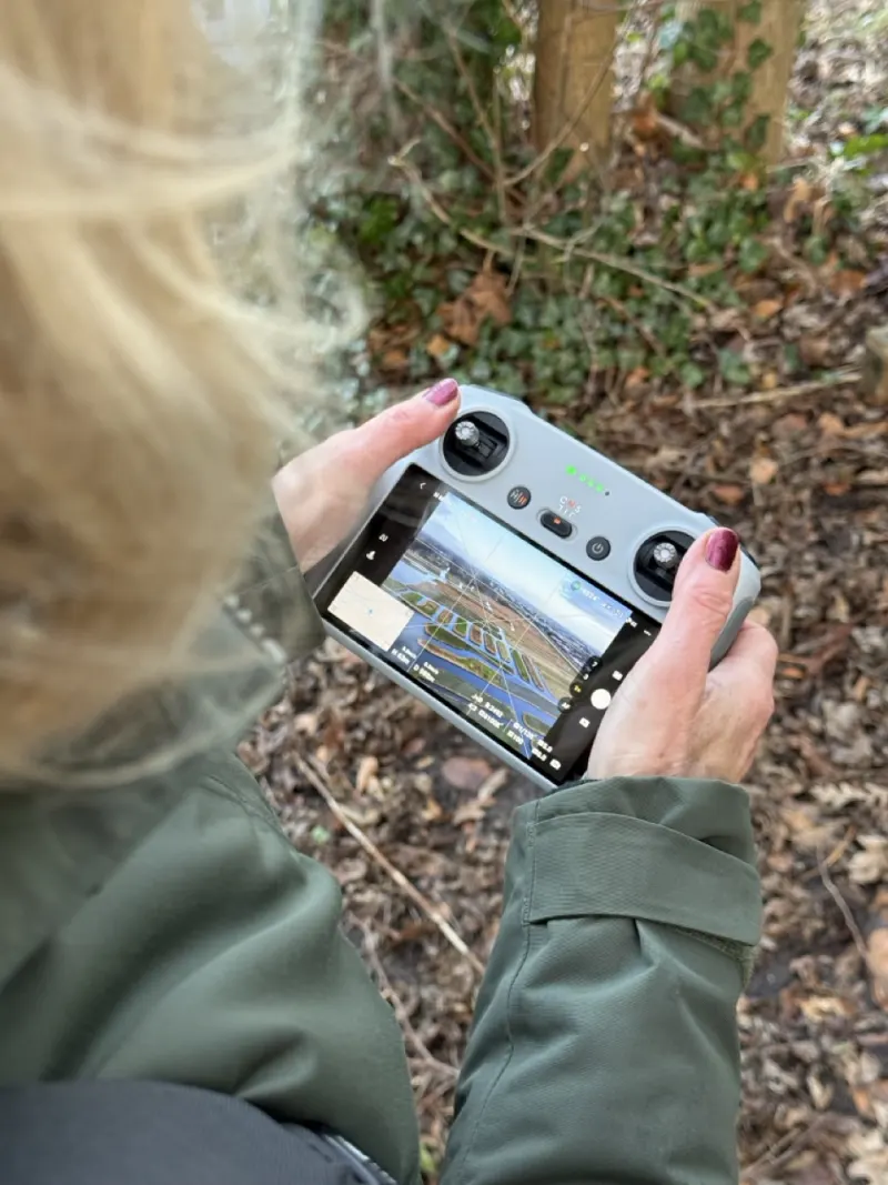 Handen met een DJI controller en live beeld van het landschap