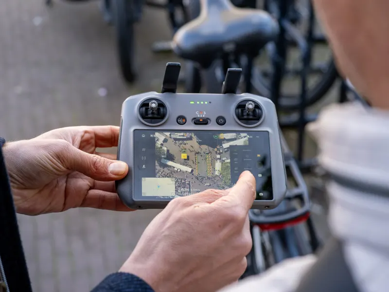 DJI controller met live beeld van een marktplein, recht van boven gefilmd met de drone