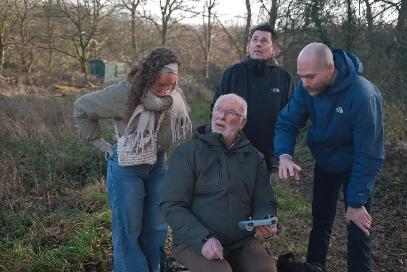 Familie kijkt mee terwijl opa de drone bestuurt