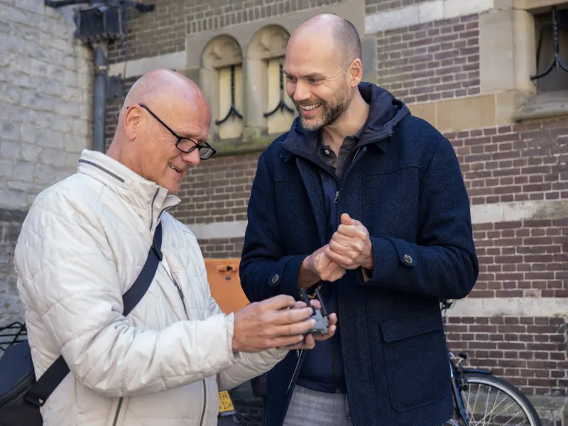 Deelnemer en docent lachen tijdens de workshop dronevliegen, de controller in handen