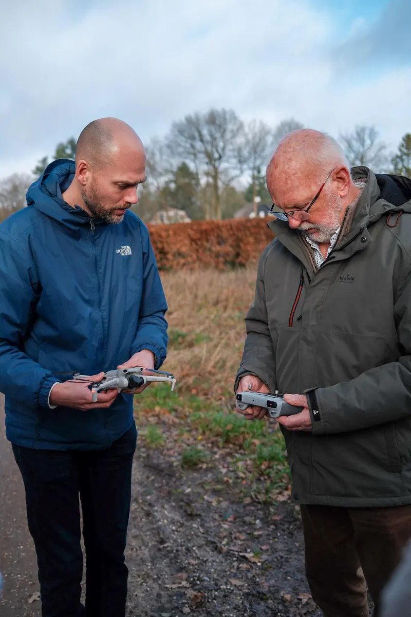Maarten legt een deelnemer de controller van de drone uit